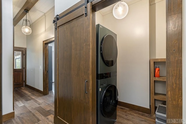 laundry room with dark wood-type flooring, stacked washer / dryer, and a barn door