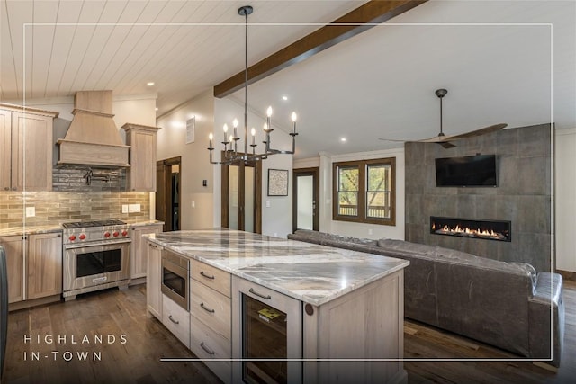 kitchen with appliances with stainless steel finishes, tasteful backsplash, custom exhaust hood, a center island, and light brown cabinets