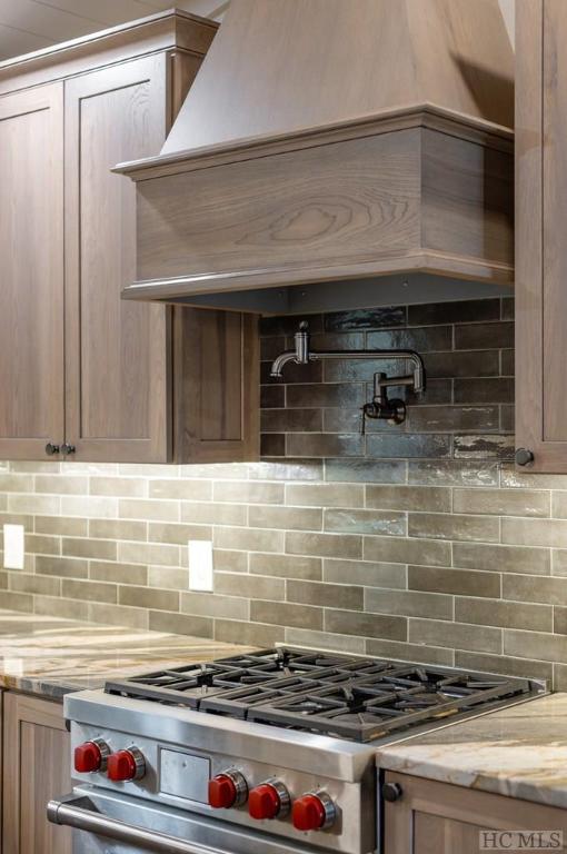 kitchen featuring tasteful backsplash, light stone countertops, and stainless steel stove