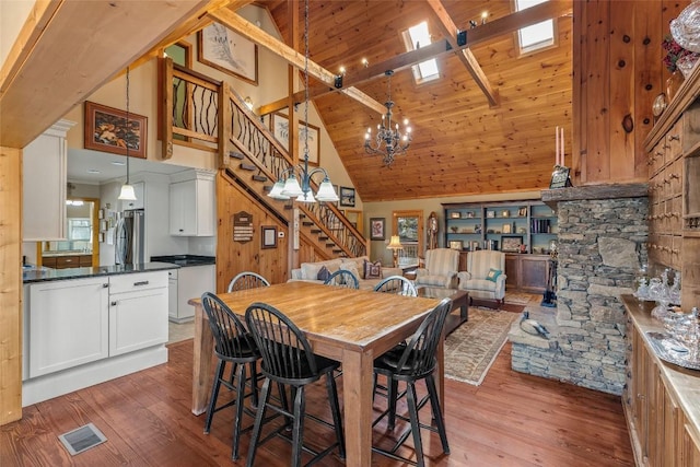 dining space with high vaulted ceiling, a notable chandelier, and wood-type flooring