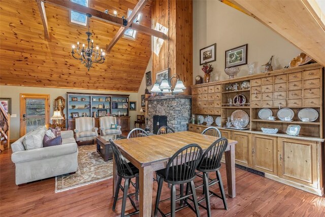 dining room featuring a fireplace, a skylight, a notable chandelier, and light hardwood / wood-style flooring