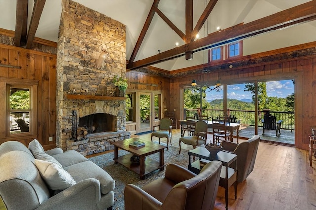 living room featuring plenty of natural light, a stone fireplace, a mountain view, wood-type flooring, and wooden walls