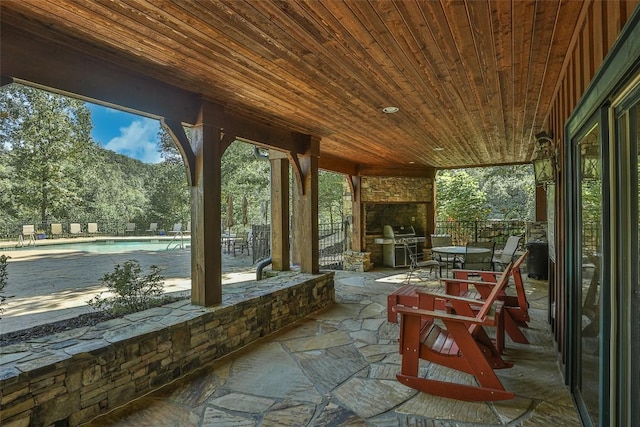 view of patio featuring a fenced in pool, area for grilling, and an outdoor stone fireplace