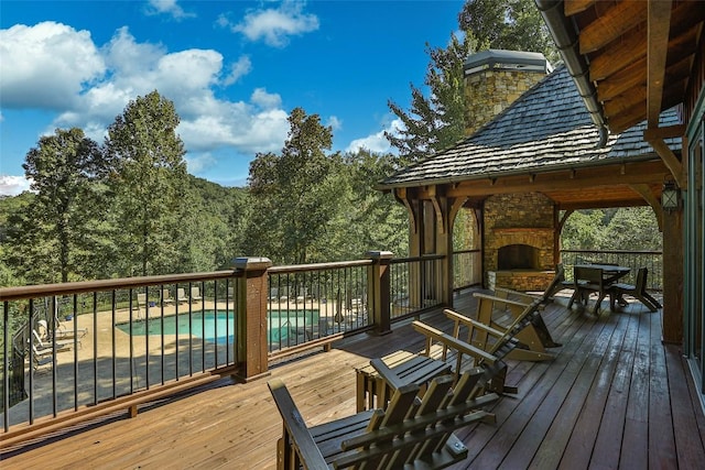 wooden deck with a fenced in pool, a gazebo, and an outdoor stone fireplace