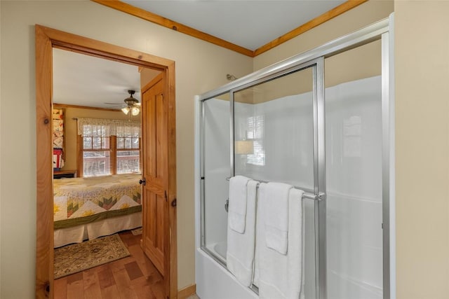 bathroom with hardwood / wood-style floors, ceiling fan, crown molding, and bath / shower combo with glass door