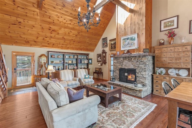 living room featuring high vaulted ceiling, a stone fireplace, an inviting chandelier, and hardwood / wood-style floors