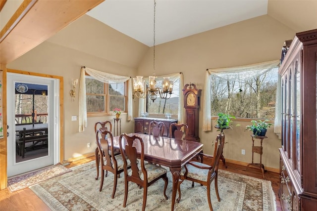 dining area with light hardwood / wood-style floors, vaulted ceiling, and a notable chandelier