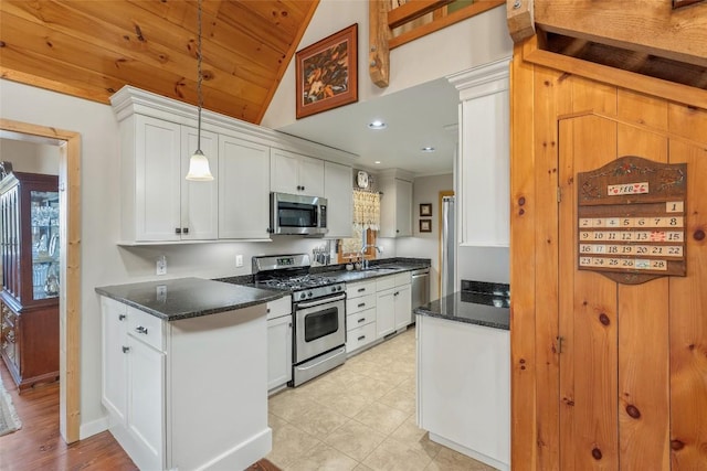 kitchen with stainless steel appliances, decorative light fixtures, sink, dark stone counters, and white cabinets