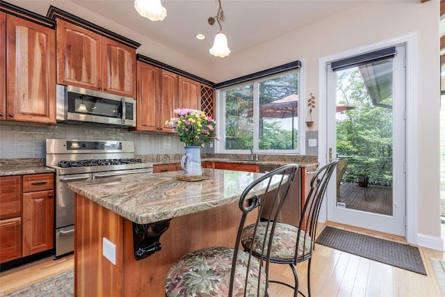135 Whisper Lake Dr, Sapphire, NC 28774 - kitchen with appliances with stainless steel finishes, light stone counters, a breakfast bar area, a center island, and light wood-style floors