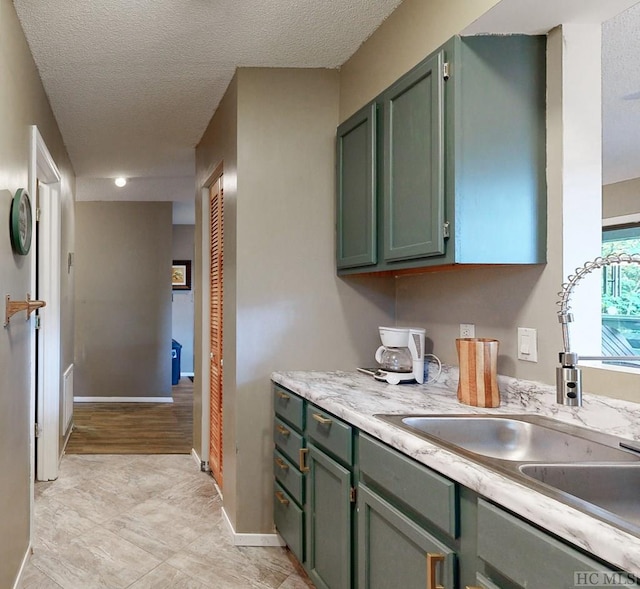 kitchen featuring sink, a textured ceiling, and green cabinets