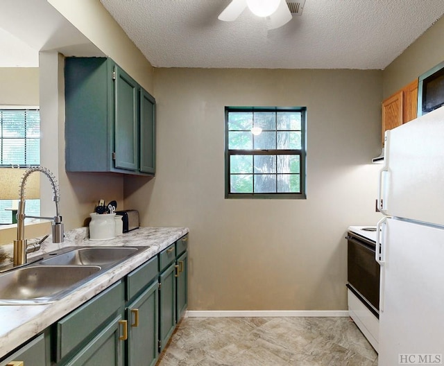 kitchen featuring ceiling fan, white appliances, sink, and a textured ceiling