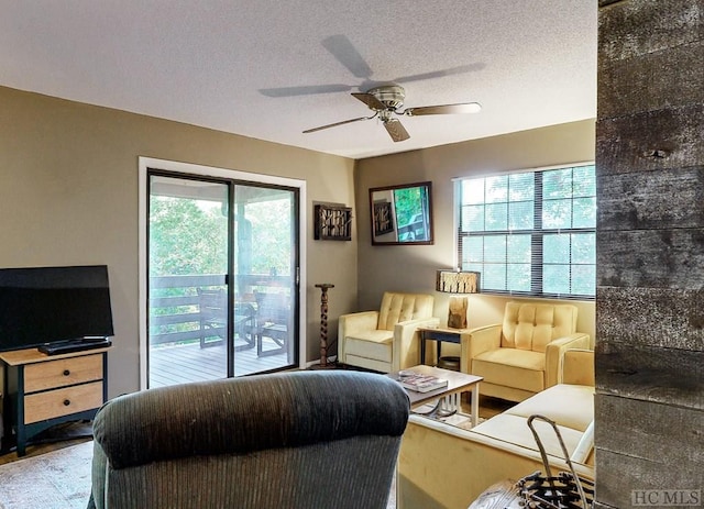 living room featuring ceiling fan and a textured ceiling