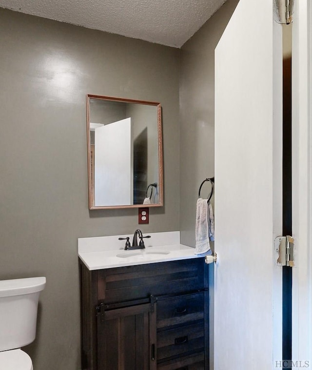 bathroom with vanity, toilet, and a textured ceiling