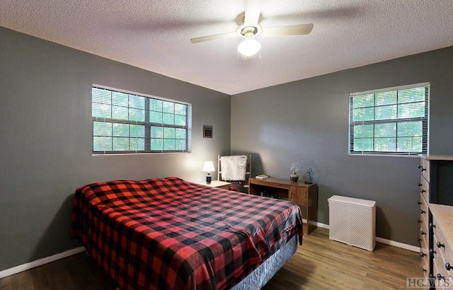 bedroom featuring multiple windows, hardwood / wood-style flooring, a textured ceiling, and ceiling fan