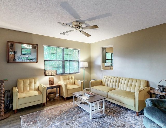 living room featuring ceiling fan, dark hardwood / wood-style flooring, and a textured ceiling