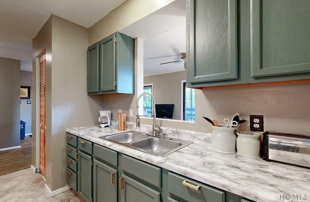 kitchen with sink, a textured ceiling, green cabinetry, and ceiling fan