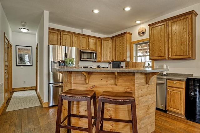 49 Lakeside Fls, Cullowhee, NC 28723 - kitchen featuring brown cabinets, dark wood-style flooring, stainless steel appliances, and a kitchen bar