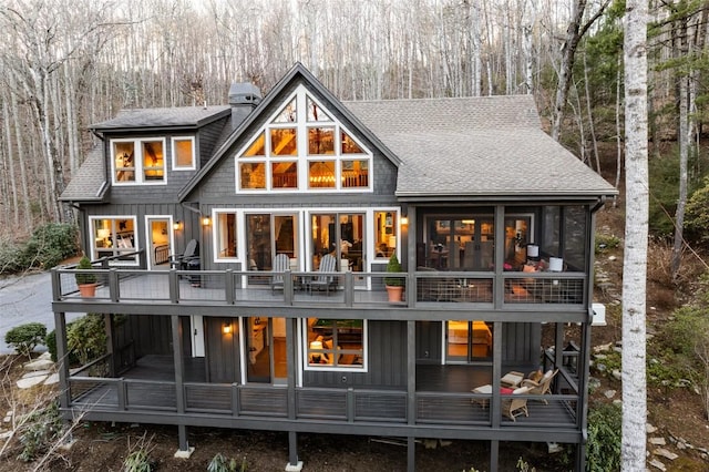 back of property featuring roof with shingles, board and batten siding, and a sunroom