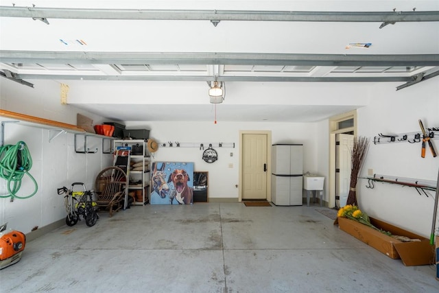 garage featuring a garage door opener, freestanding refrigerator, and a sink