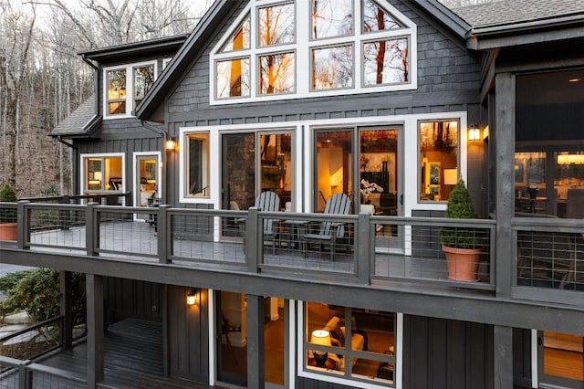 rear view of property with a balcony, board and batten siding, and a shingled roof