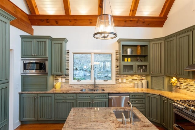 kitchen featuring light stone counters, a sink, appliances with stainless steel finishes, and green cabinetry