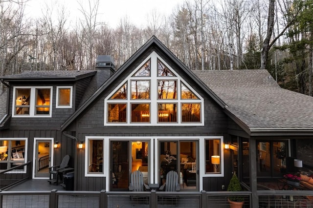 back of property with a chimney, board and batten siding, a sunroom, and a shingled roof