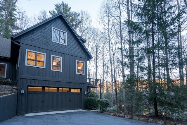 exterior space with board and batten siding, an attached garage, and driveway