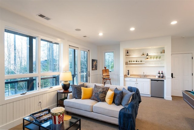 living room featuring light carpet, visible vents, recessed lighting, and wet bar