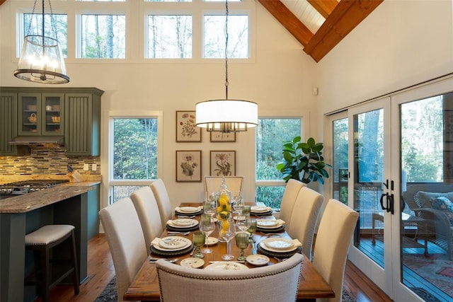 dining space with french doors, beam ceiling, high vaulted ceiling, and wood finished floors