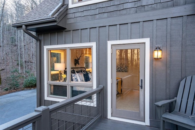 doorway to property with board and batten siding and roof with shingles