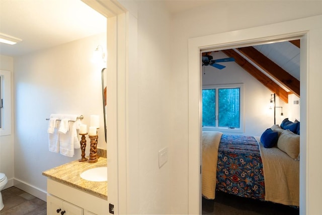 bedroom featuring wood finished floors, lofted ceiling with beams, baseboards, and a sink