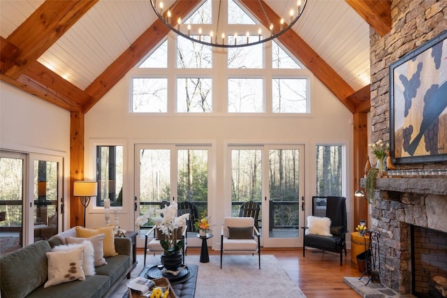 living room with wood ceiling, a wealth of natural light, a fireplace, an inviting chandelier, and wood finished floors