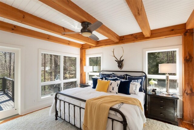 dining space featuring beam ceiling, high vaulted ceiling, wood finished floors, a fireplace, and a chandelier