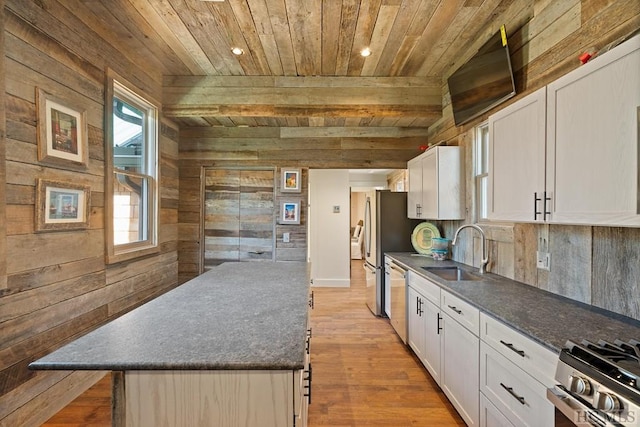 kitchen with stainless steel appliances, wood walls, sink, wooden ceiling, and white cabinets