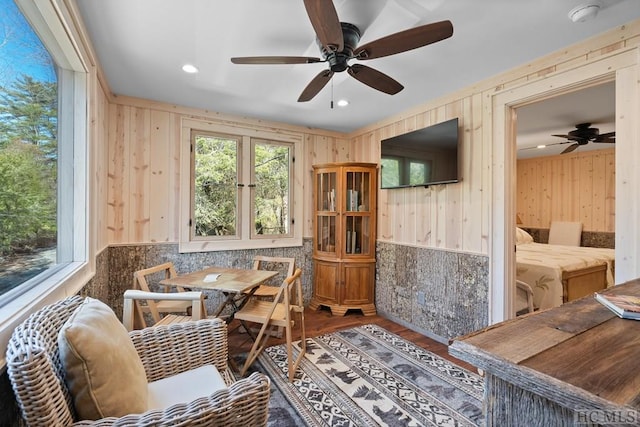 dining area featuring hardwood / wood-style flooring, wood walls, and a healthy amount of sunlight