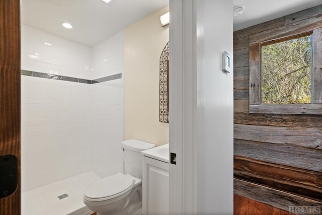 bathroom with a tile shower, vanity, and toilet