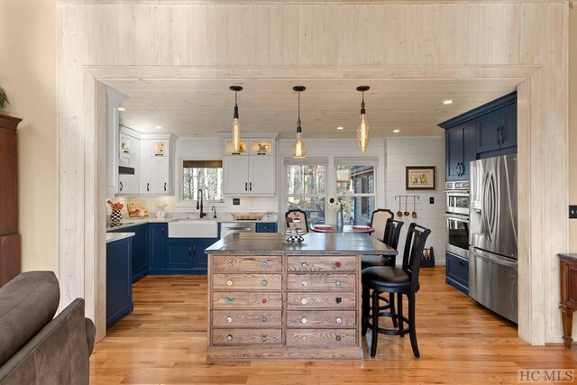 kitchen with stainless steel appliances, sink, blue cabinets, and white cabinets