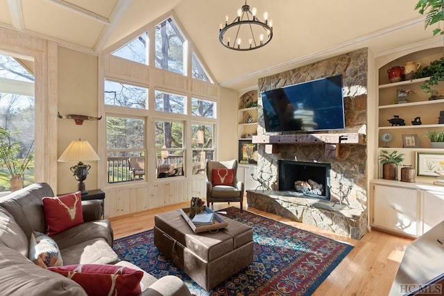 living room with lofted ceiling, a notable chandelier, light wood-type flooring, a fireplace, and built in features