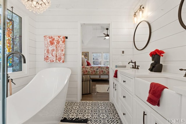 bathroom with vanity, plenty of natural light, wooden walls, and a bathing tub