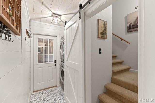 entryway featuring a barn door and stacked washer / dryer