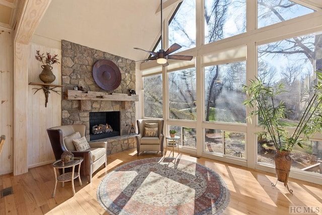 sunroom featuring a fireplace, ceiling fan, vaulted ceiling, and plenty of natural light