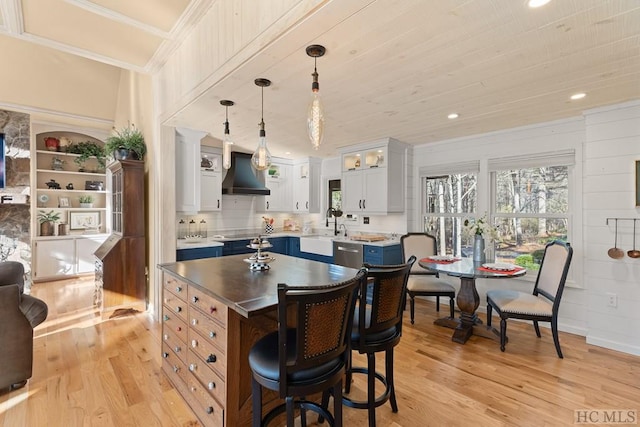 kitchen with hanging light fixtures, wall chimney exhaust hood, blue cabinetry, white cabinets, and a center island