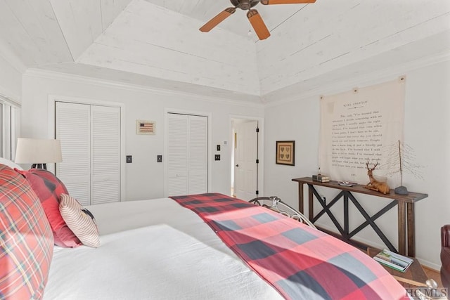 bedroom featuring a towering ceiling, two closets, ceiling fan, a raised ceiling, and crown molding