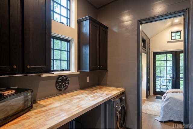 laundry room with washer / dryer, cabinets, a healthy amount of sunlight, and light wood-type flooring