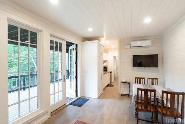 interior space with a wall mounted AC, wood ceiling, light wood-type flooring, and wood walls