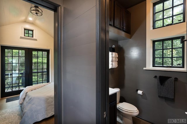 bathroom with french doors, vanity, toilet, and vaulted ceiling