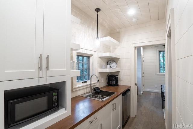 kitchen featuring butcher block counters, sink, white cabinetry, hanging light fixtures, and dishwasher