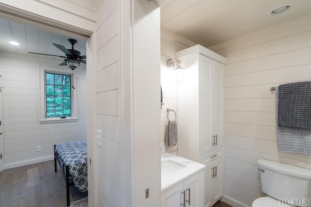 bathroom featuring vanity, hardwood / wood-style floors, ceiling fan, and wood walls