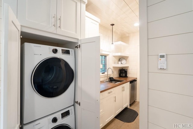 clothes washing area with sink, light hardwood / wood-style flooring, and stacked washing maching and dryer