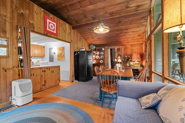 dining space featuring wooden walls, lofted ceiling, light wood finished floors, and wooden ceiling